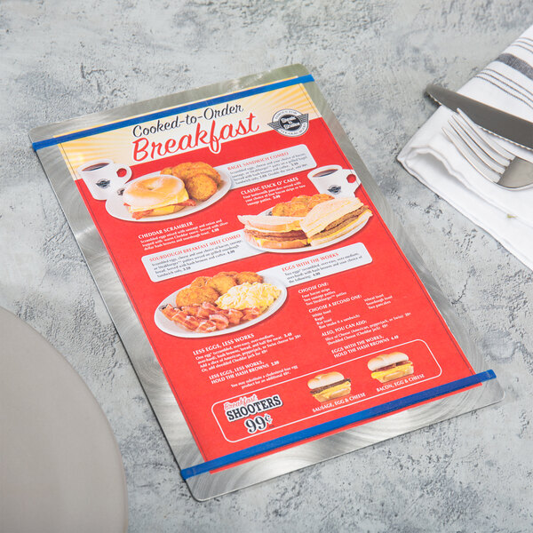 A Menu Solutions Alumitique menu board with navy bands on a table with a fork and knife on it.