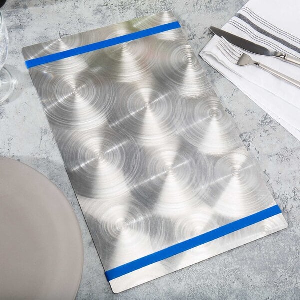 An Alumitique menu board with royal blue bands on a table with silverware on a white napkin.