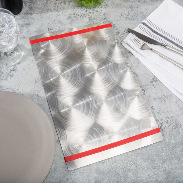 A silver plate with a Menu Solutions Alumitique red band on a table with silverware.