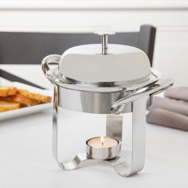 A Libbey stainless steel chafing dish with a candle on a white table.
