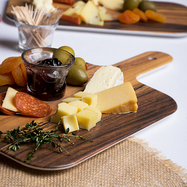 An American Metalcraft faux acacia melamine serving peel with cheese, olives, and other food on a table.