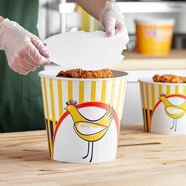 A person putting food in a Choice chicken bucket.