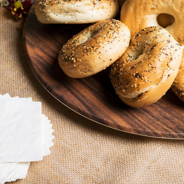 An American Metalcraft faux acacia melamine serving board with bagels and napkins on a table.