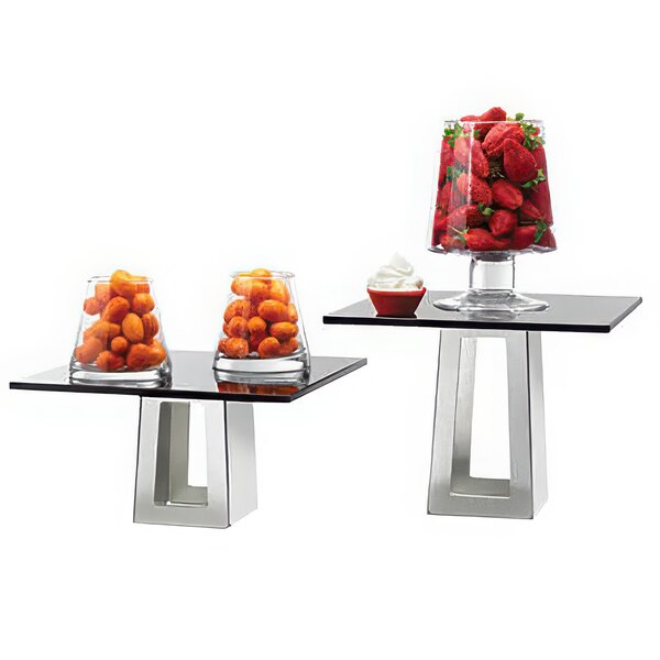 Two Rosseto black tempered glass and metal risers with glass containers of strawberries and oranges on a table.
