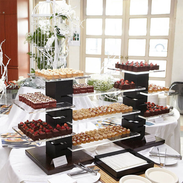 A table with a Rosseto black matte steel and walnut multi-level riser holding desserts.