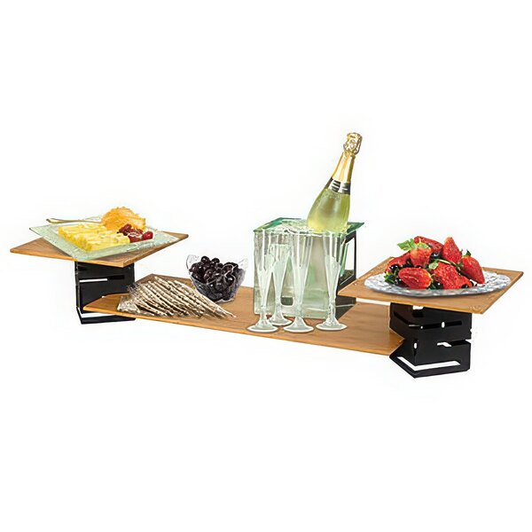A Rosseto square bamboo riser on a table with champagne glasses, wine, and fruit.
