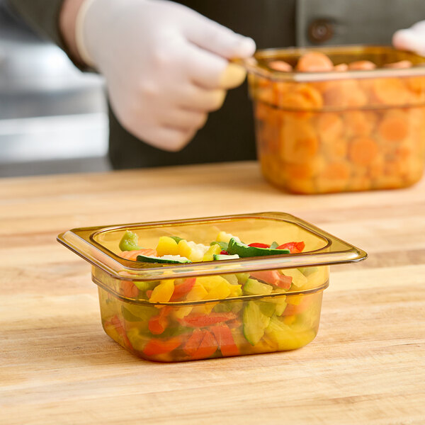A person wearing gloves holding a Cambro plastic food pan with food in it.