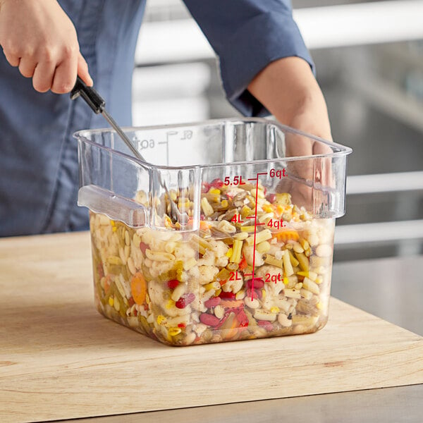 A person cutting up food in a Choice square food storage container.