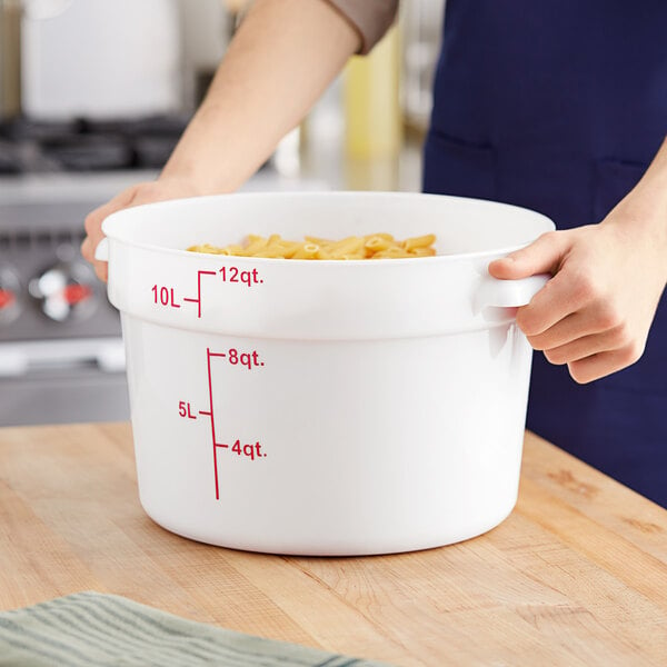 A woman holding a large white Choice food storage container full of pasta.