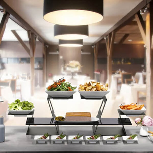 A buffet table with food served in white square Rosseto porcelain bowls.