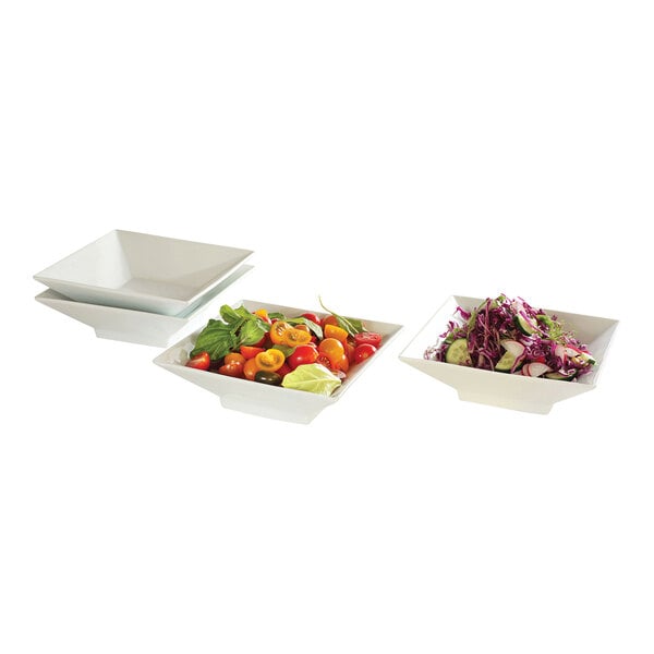 A stack of four square white Rosseto porcelain bowls with salads and vegetables.