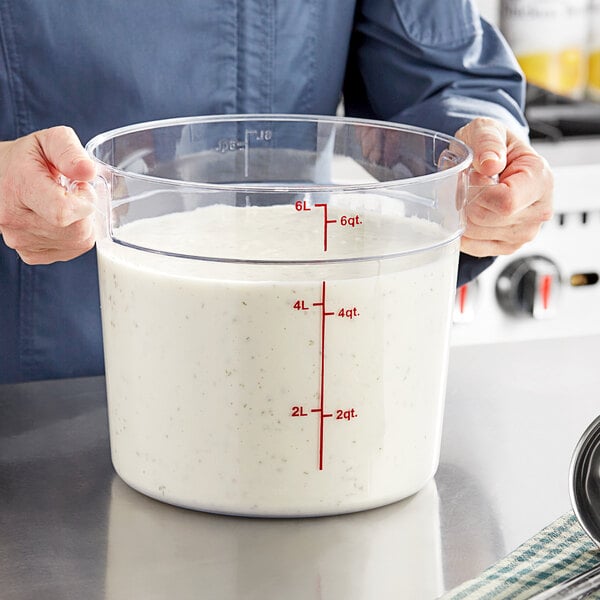 A woman holding a measuring cup with white liquid in a white container with red text.