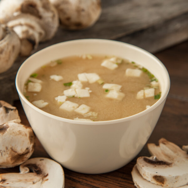 A tan Carlisle Kingline melamine bouillon cup filled with soup and mushrooms.