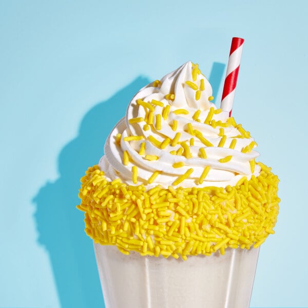 A cup of yellow and white milkshake with Adourne yellow sprinkles.