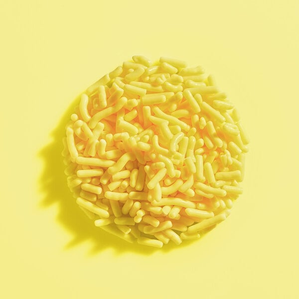 A pile of yellow sprinkles arranged in a circular shape on a yellow background.
