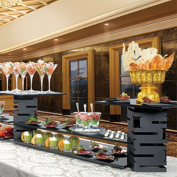 A Rosseto black acrylic narrow riser shelf displaying food and drinks on a buffet table.