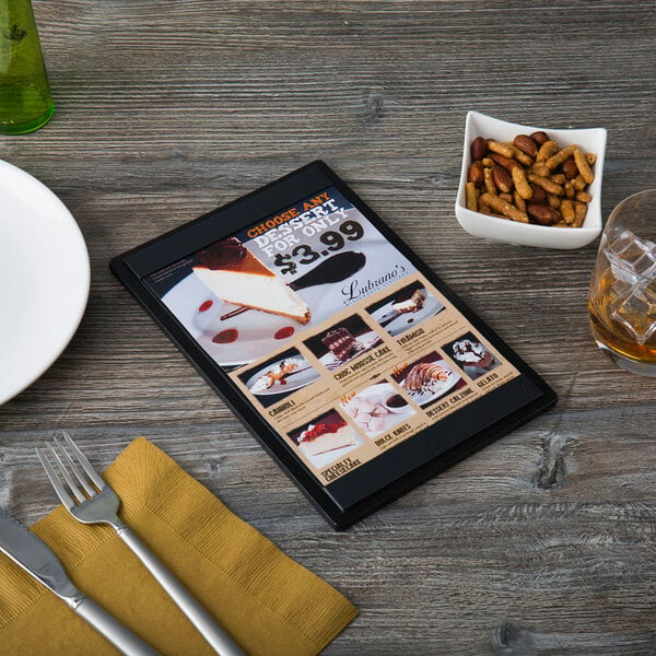 A customizable wood menu board on a table with a menu and utensils.