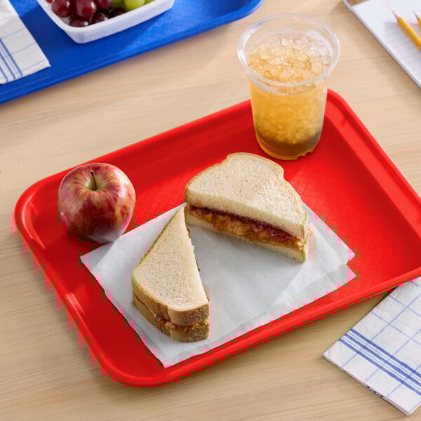 A red plastic fast food tray holding a sandwich, an apple, and a cup of iced beverage.