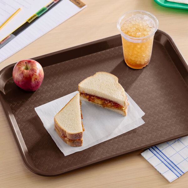 A rectangular chocolate brown plastic fast food tray holding a sandwich, an apple, and a cup of iced beverage.