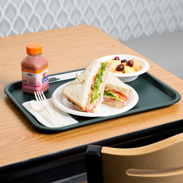 A forest green plastic fast food tray with a sandwich and fruit on it.