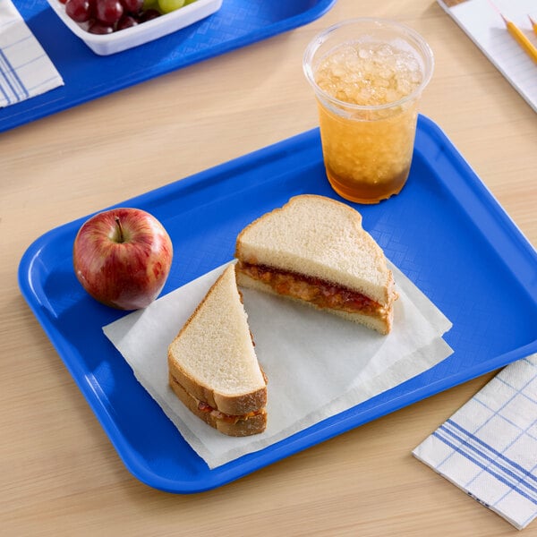 A blue plastic fast food tray holding a peanut butter and jelly sandwich, an apple, and a cup of iced beverage.