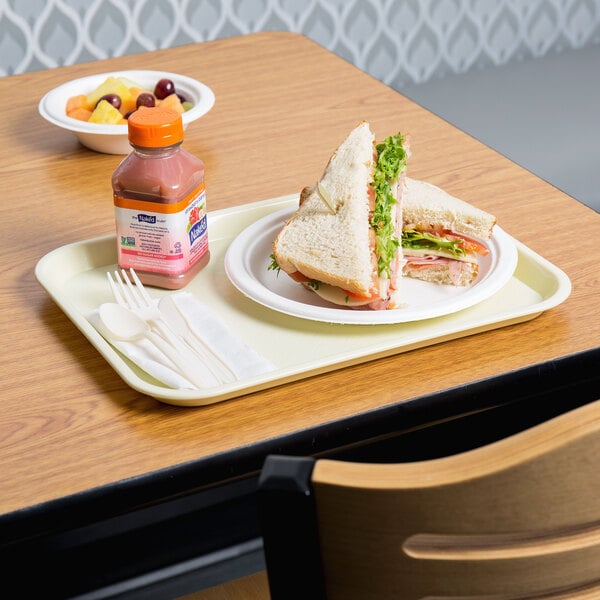 A sandwich and a bottle of juice on a beige plastic fast food tray with a white plastic fork.