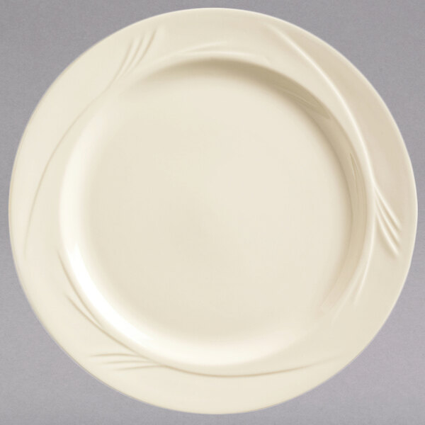 A Libbey round cream white medium rim china plate with a swirl design on the rim.