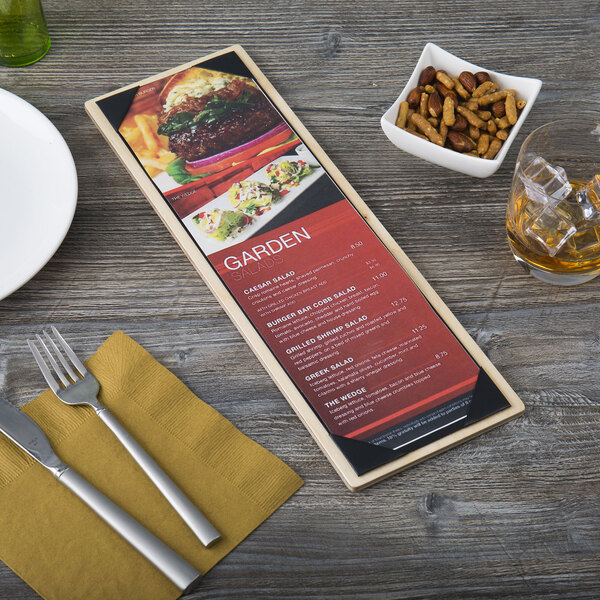 A customizable wood menu board on a table with a knife and fork and a picture of a burger.