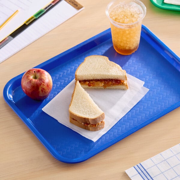 A blue plastic fast food tray holding a peanut butter and jelly sandwich, an apple, and a cup of iced beverage.