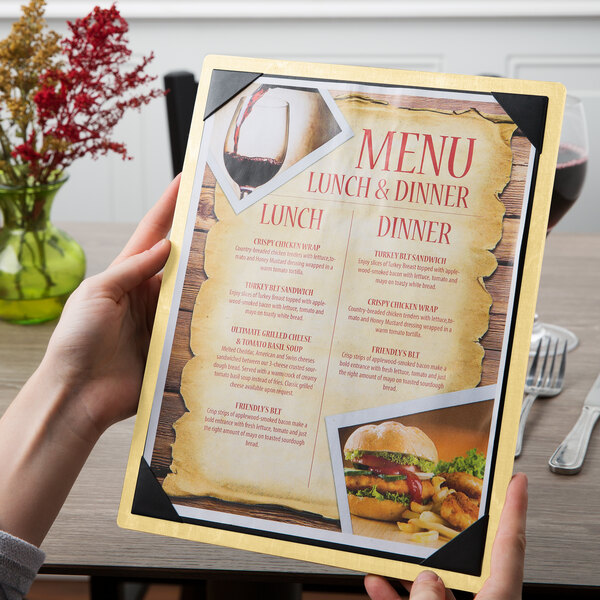A hand holding a Menu Solutions customizable wood menu board with picture corners.