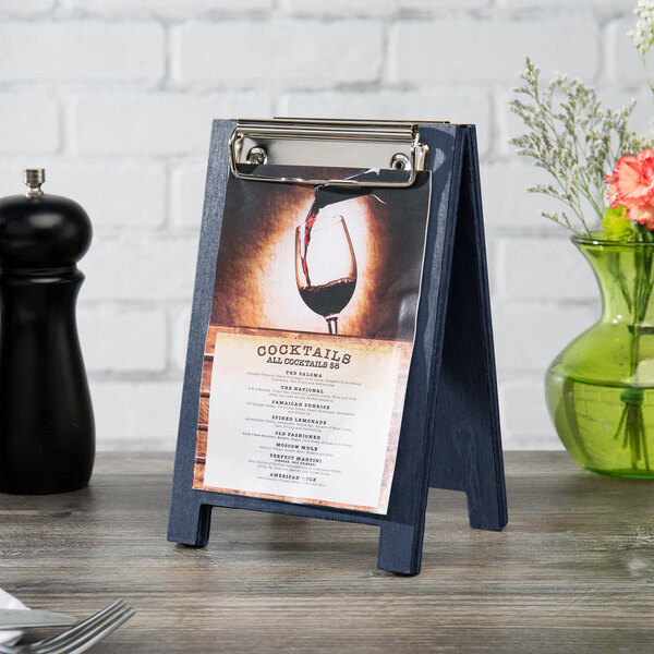 A Menu Solutions denim wood sandwich menu board tent with a clip holding a menu.
