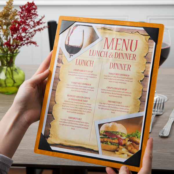 A person holding a Menu Solutions country oak wood menu board with picture corners.