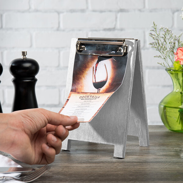 Menu Solutions white wash wood sandwich menu board tent with clip being held on a table.