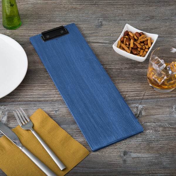 A wooden table with a Menu Solutions wood clip board holding a menu.