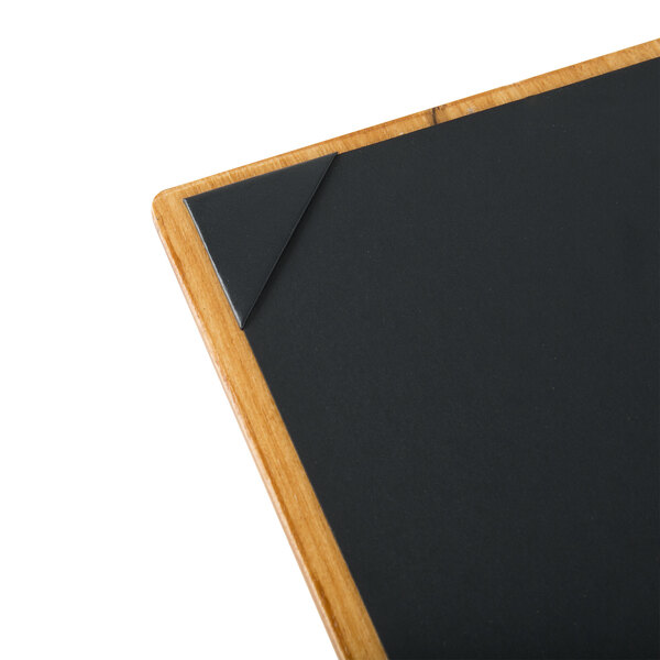 A customizable wood menu board with picture corners on a table.