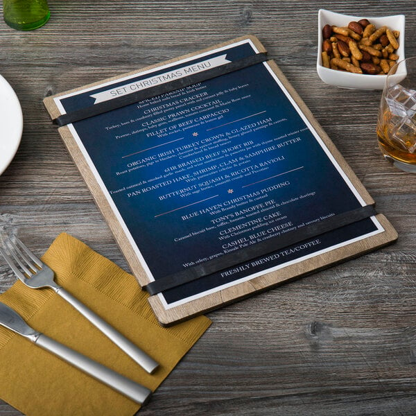 A customizable wood menu board with rubber band straps on a wood table with a menu displayed.