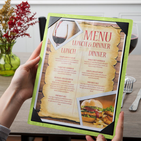 A hand holding a Menu Solutions wood menu board with a lime green corner.