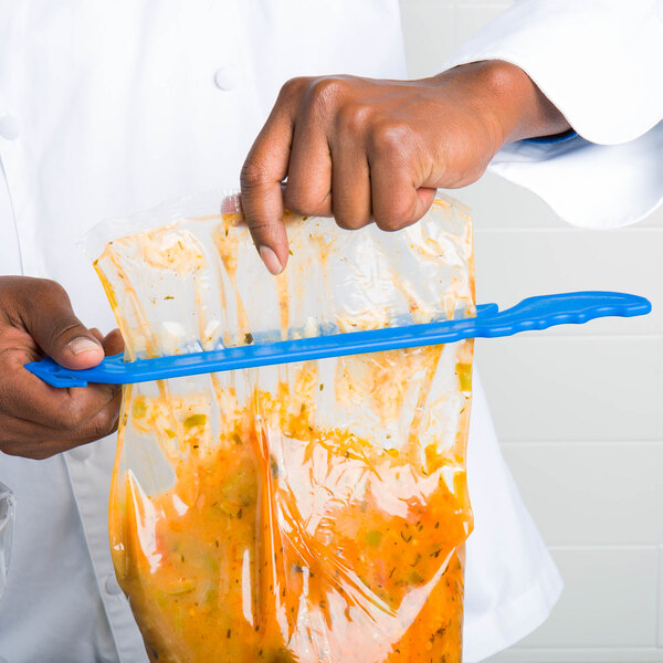 A person using a San Jamar blue Bag Boa to hold a plastic bag of food.