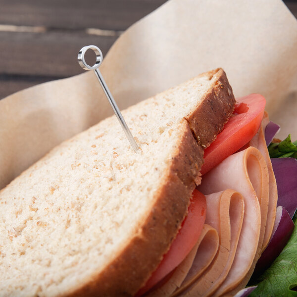A sandwich with a Barfly stainless steel cocktail pick with a circle top in it.