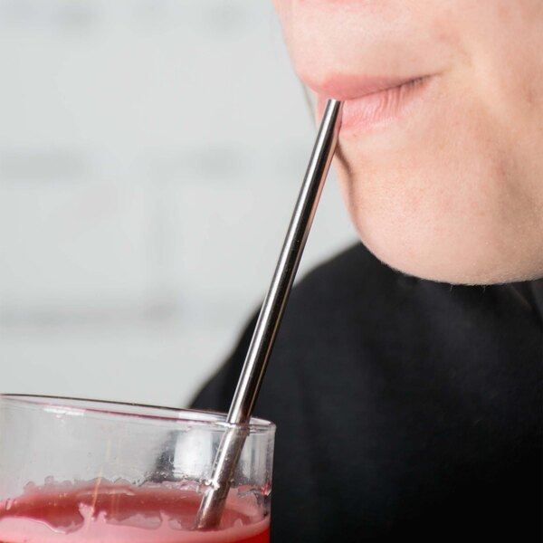 A woman drinking from a glass with a Barfly stainless steel straw.