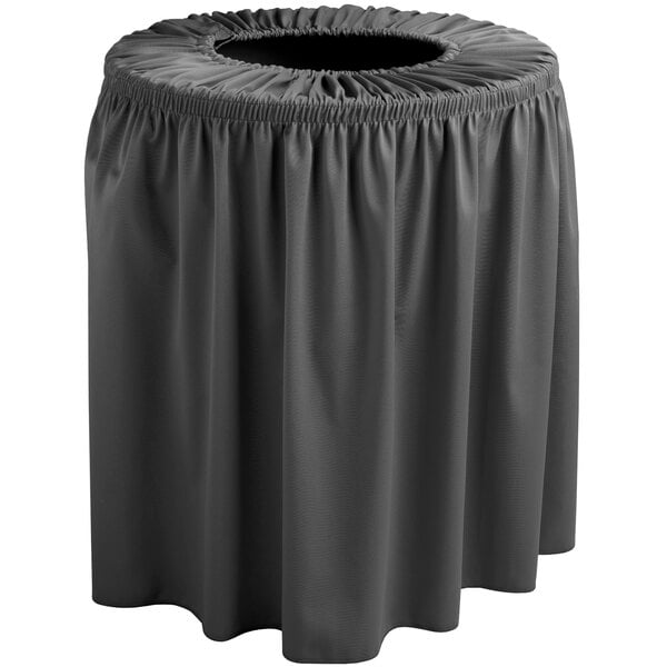 A black round trash can covered with a black shirred pleat cover on a grey table.