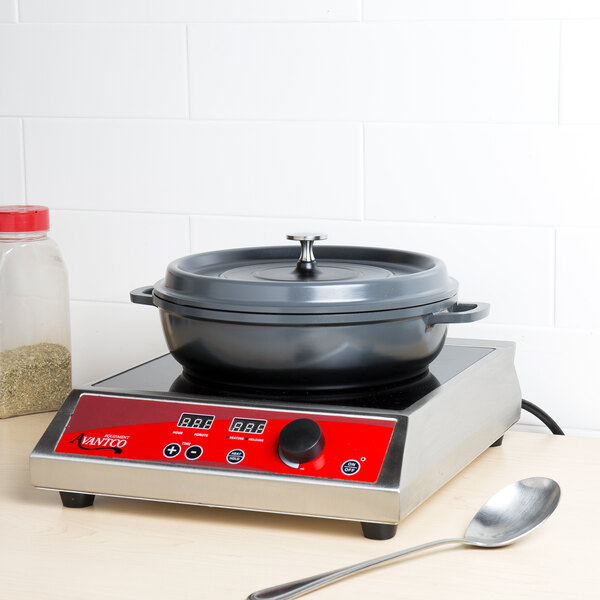 A gray GET enamel coated cast aluminum brazier with lid on a red electric stove.