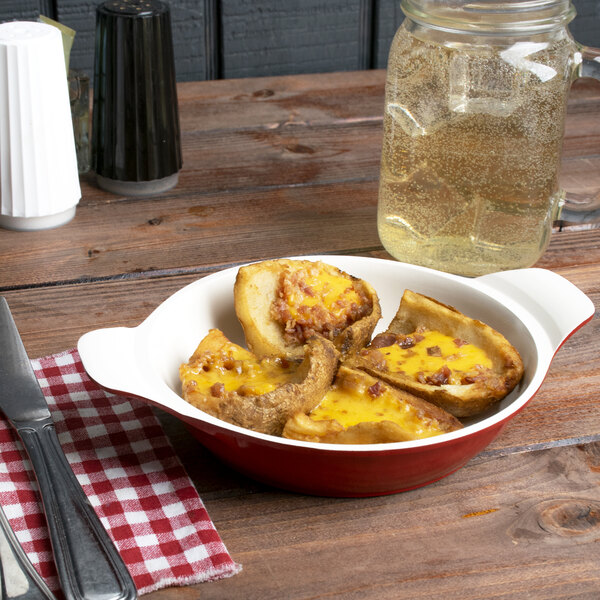 A bowl of potatoes and cheese in a red and white enamel round pan.