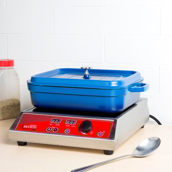 A cobalt blue GET roasting pan with a lid on a metal surface.