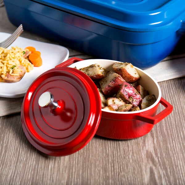 A red GET enamel oval pot with a lid filled with food next to a plate of rice and a blue container.