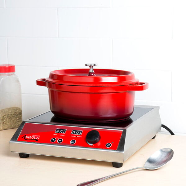 A red enamel oval Dutch oven with a lid and a black and red handle.