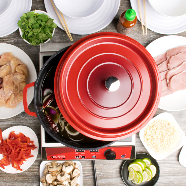 A red GET Heiss cast aluminum dutch oven with a lid on a table with food.