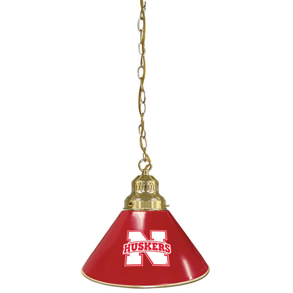 A red lamp shade with a white N and a brass pendant light with a Nebraska Huskers logo.