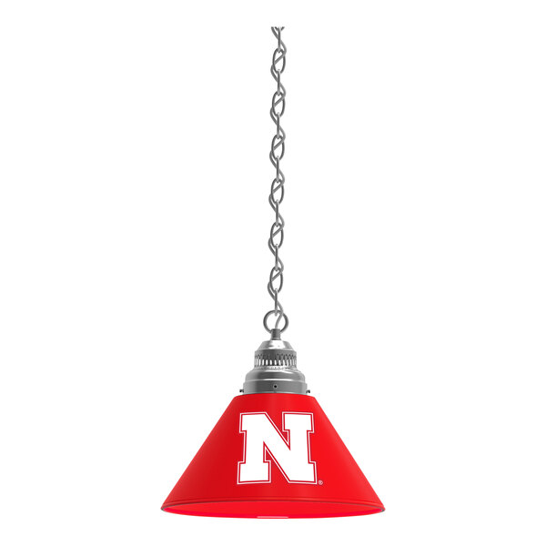 A red lamp shade with a white University of Nebraska logo on it.