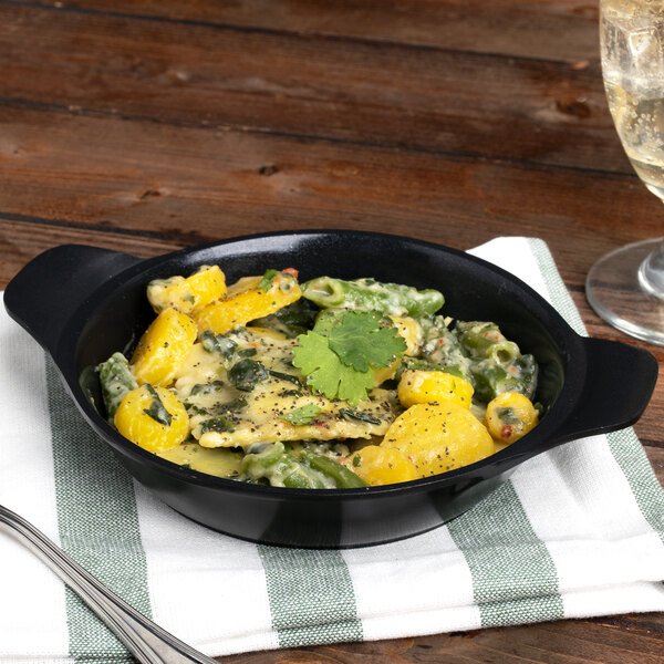 A black enamel coated round pan filled with food on a table.